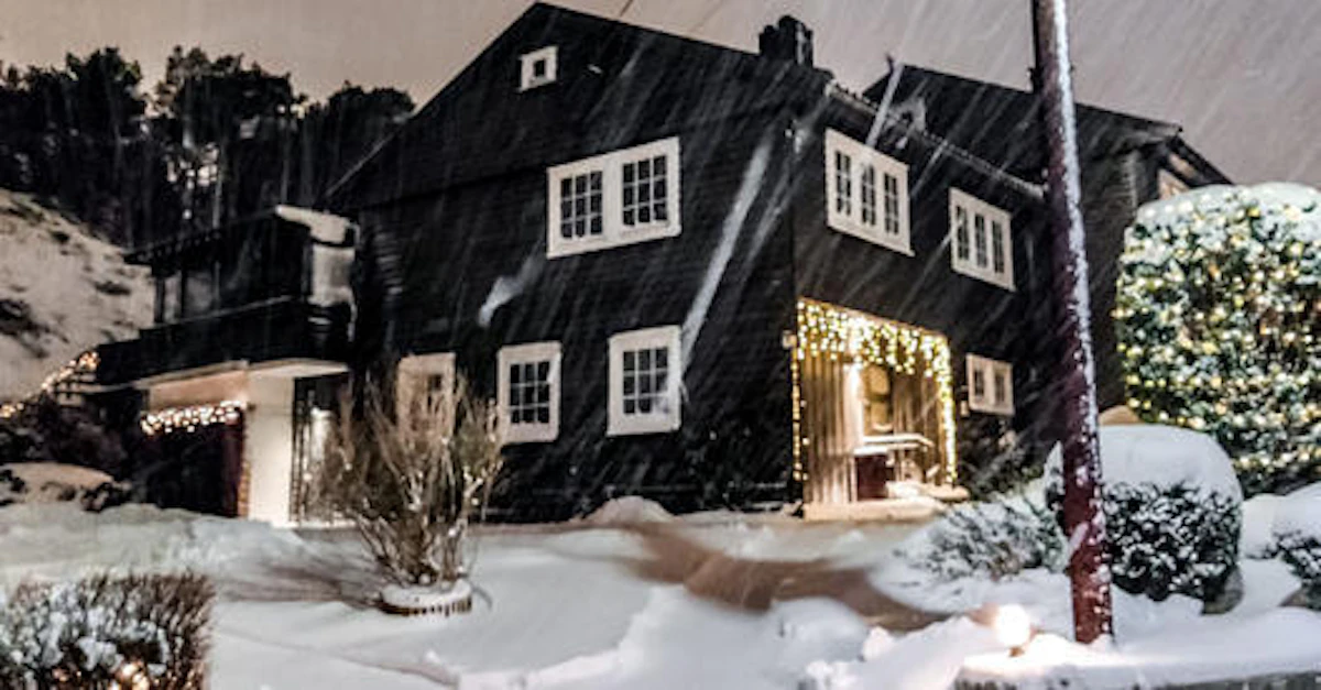 Et mørk hus, men med flott lyssetting i vinterlandskap. Foto