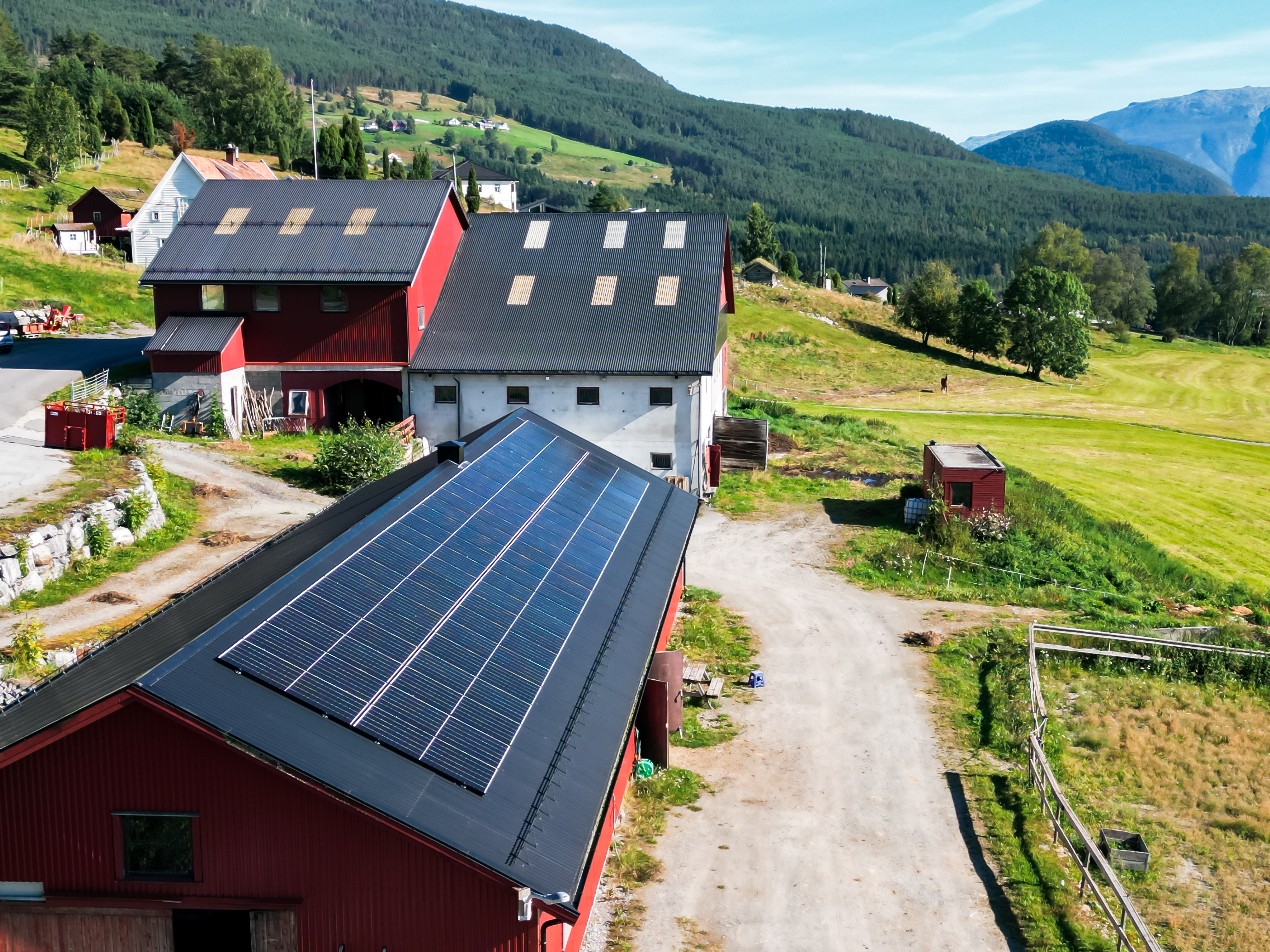 En stor gård med elektroinstallasjoner og solceller på taket. Dronebilde.