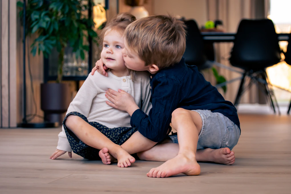 Gulvoppvarming visualisert med to barn som sitter på et varmt gulv