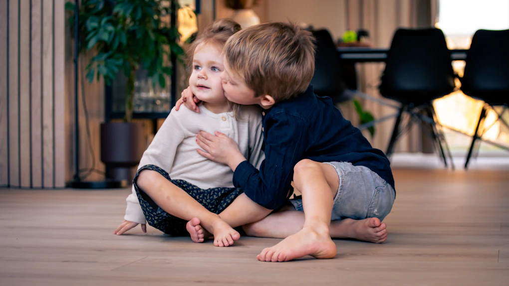 Gulvoppvarming visualisert med to barn som sitter på et varmt gulv. Foto