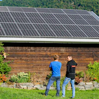 Martin og Frank står mot et av de to store solcelleanleggene til Martin. Foto.
