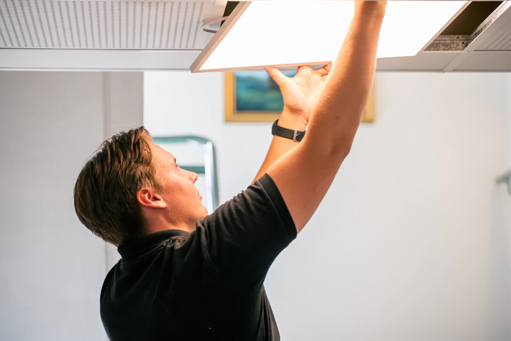 Elektriker Fredrik i Installasjonssverice, bytter ut gamle lysstoffrør med nye LED-lys. Foto.