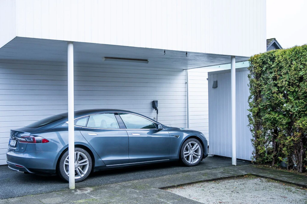 Tesla som står til lading i en carport. Foto