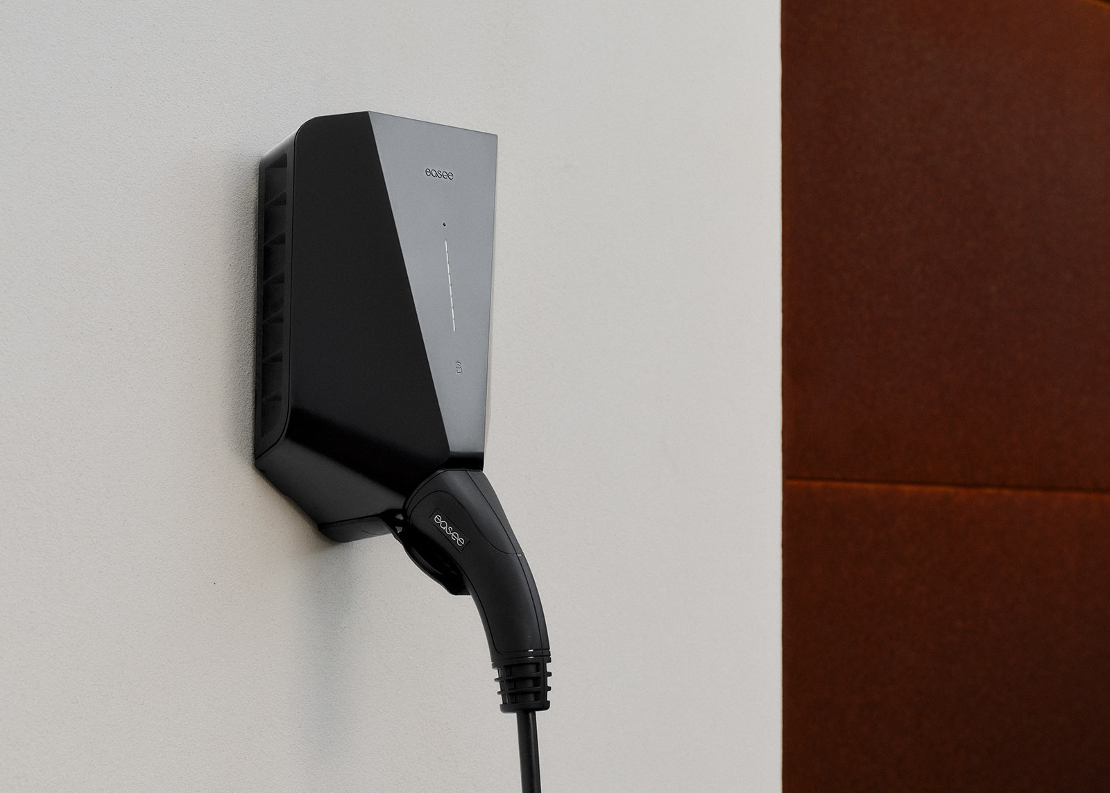 Easee lader på hvit vegg, med tilkoblet ladekabel.