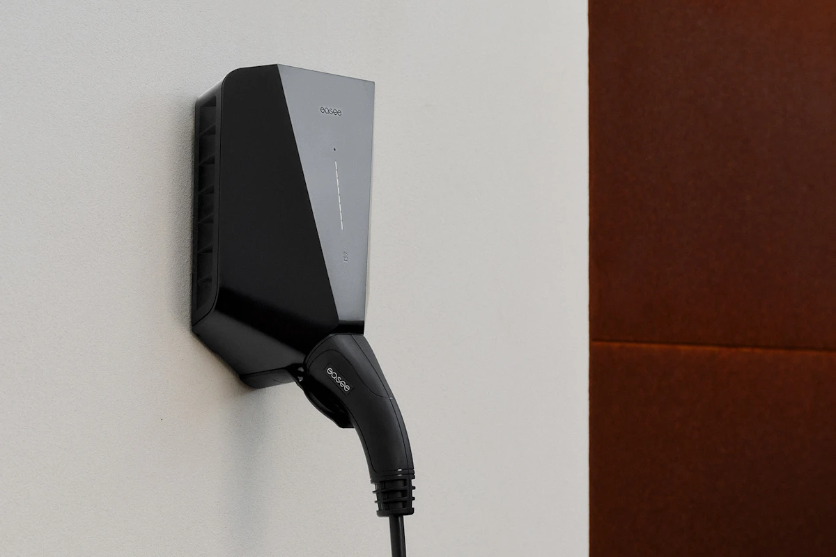 Easee lader på hvit vegg, med tilkoblet ladekabel.