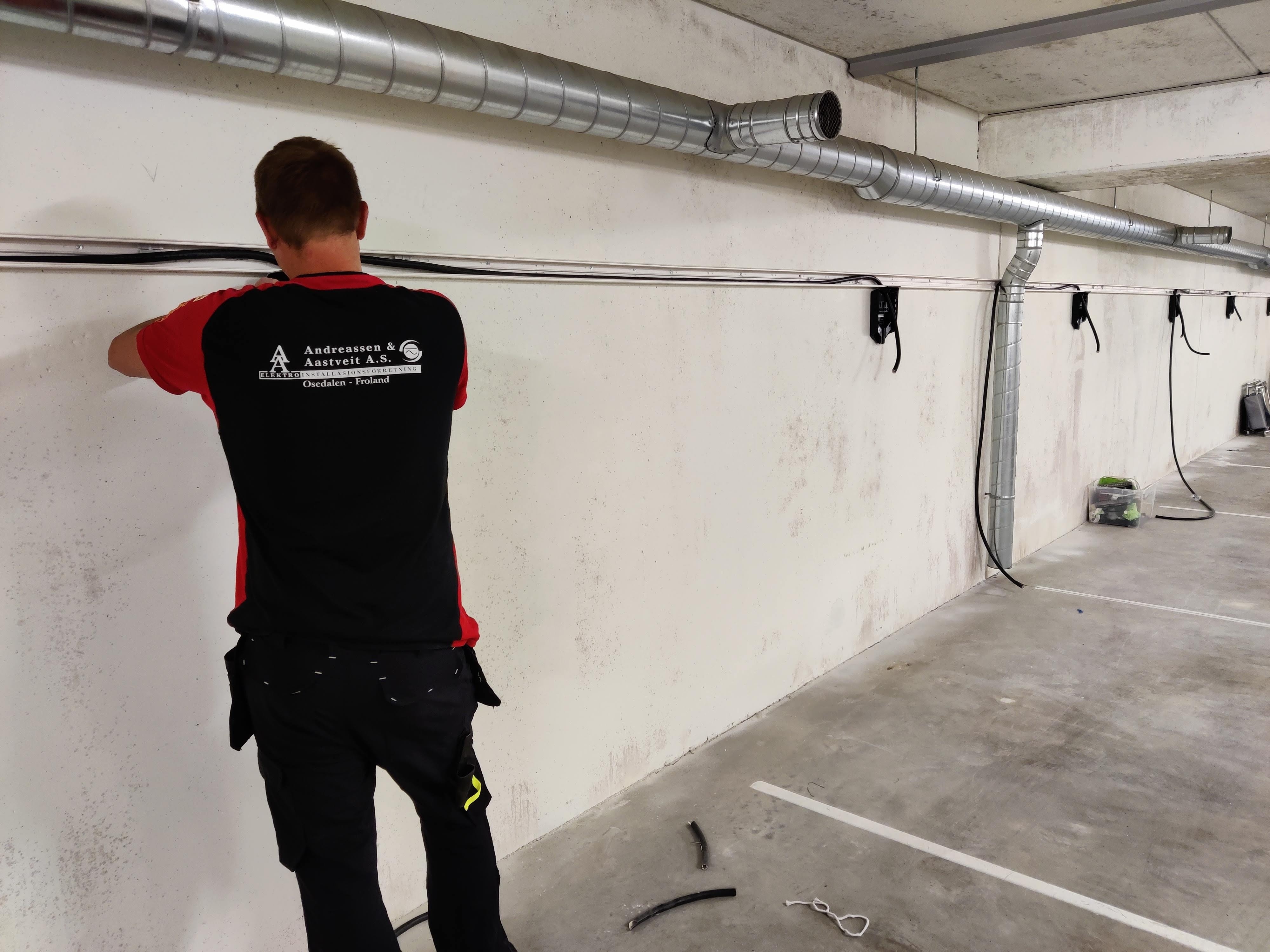 En av våre elektrikere installerer elbilladere i garasjeanlegg. Foto.