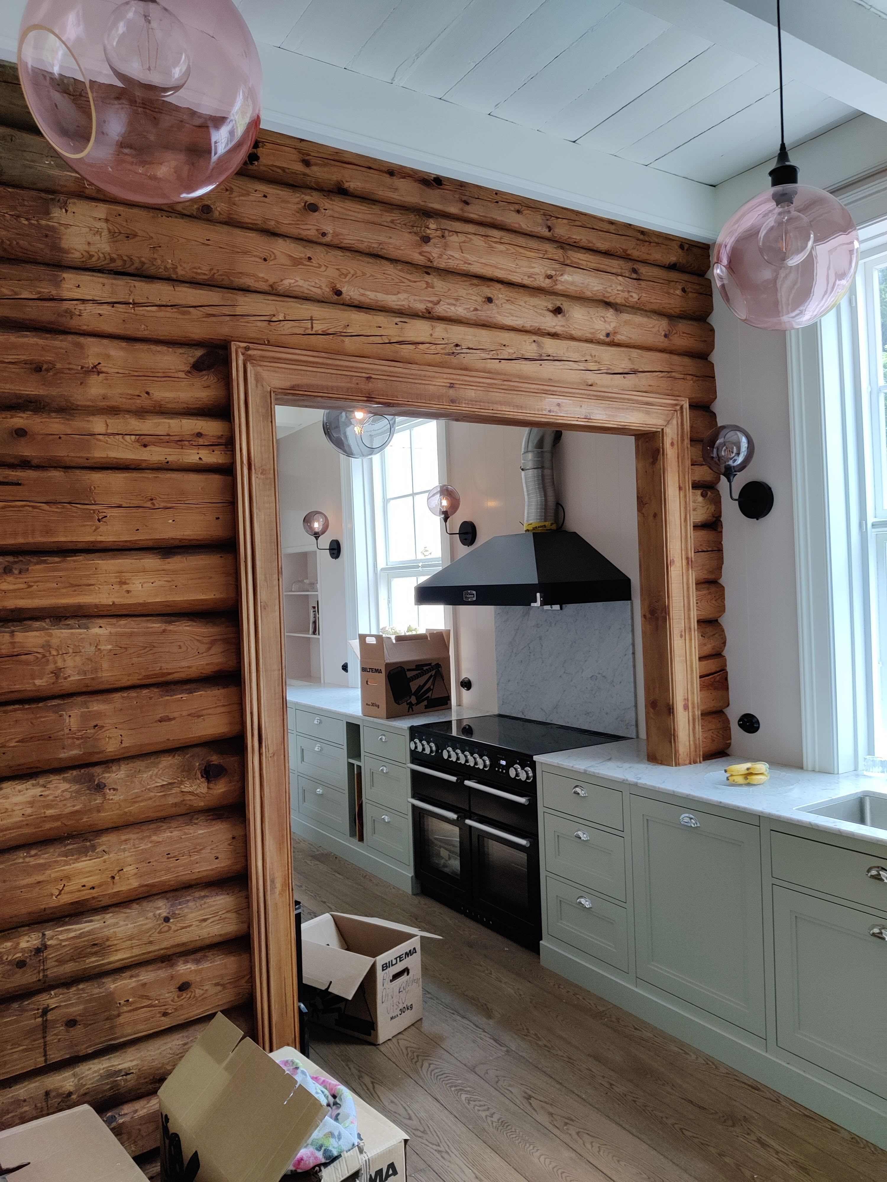 Kjøkken sett fra motsatt vinkel. Store runde taklamper og vegglamper. Foto,