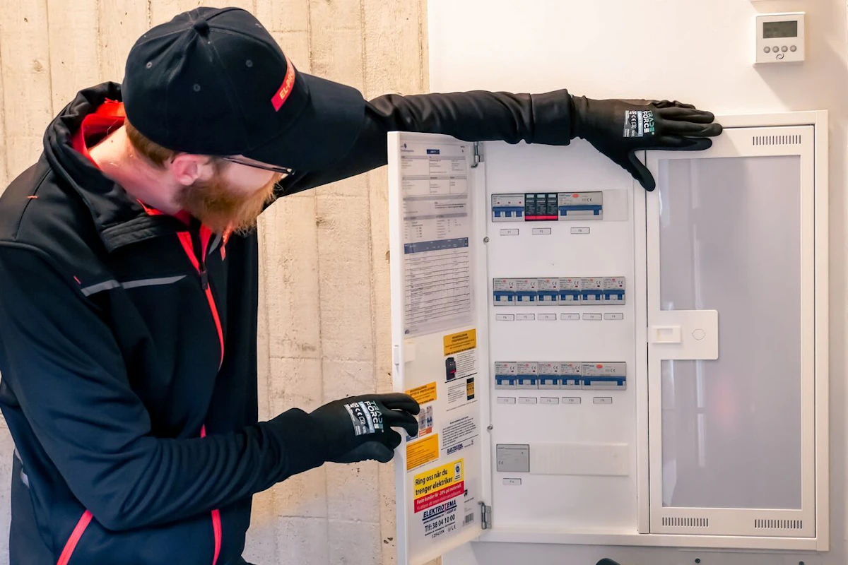 en mann i el-proffenklær kikker inn i et sikringsskap. foto