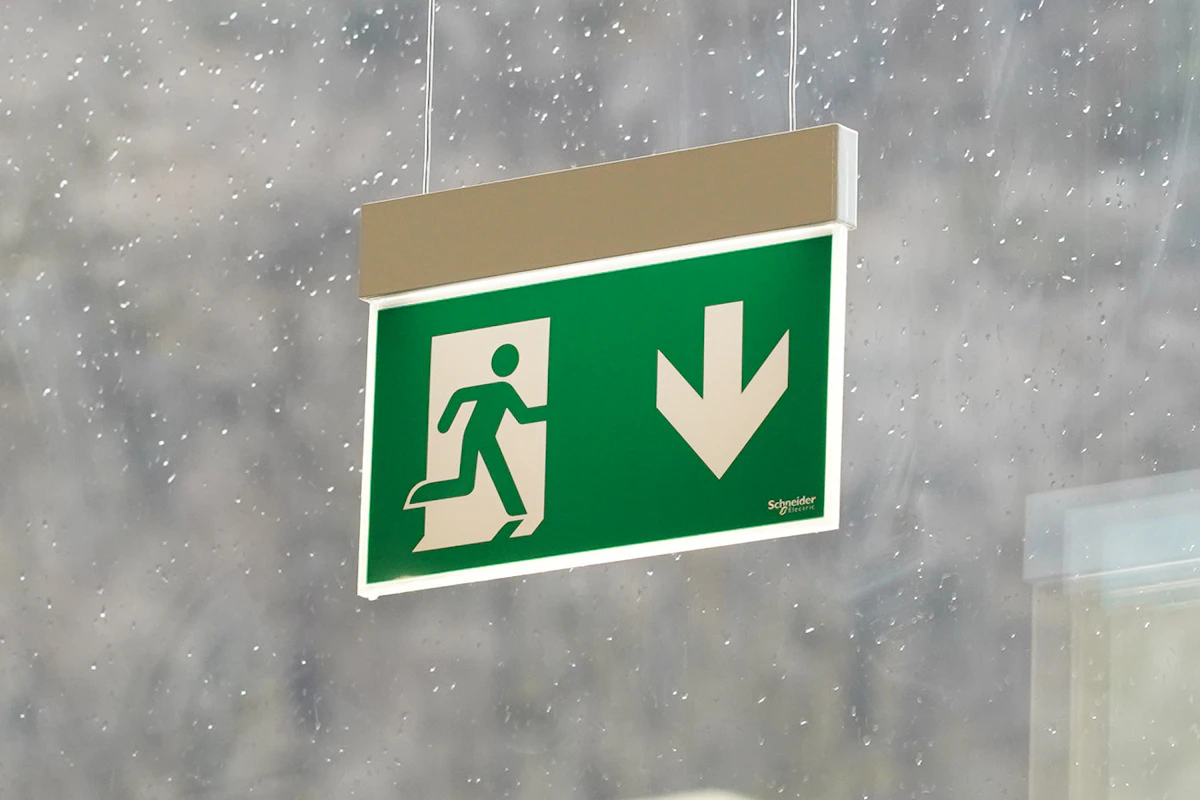 Nødlys i serien Exiway fra Schneider Electric, som henger i et vindu. Foto.
