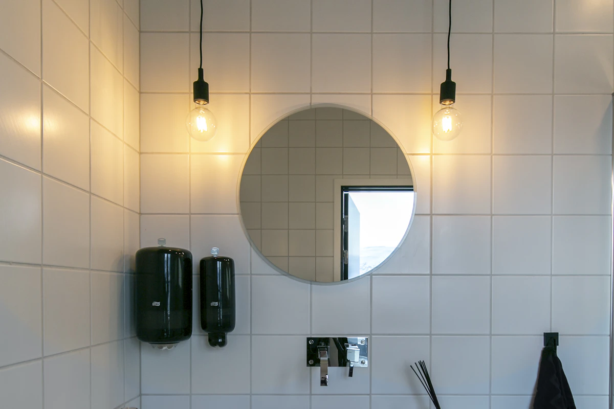 Annerledes belysning på badet med to lyspærer hengende ned på hver side av speilet.