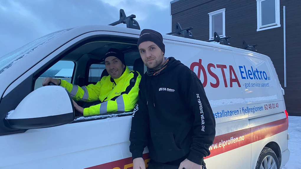 Bilde av Østa Elektro sine ansatte Vebjørn Lillebo og Roar Tangen i bil foran bygget ved hovedkontoret på Tynset, Bilde
