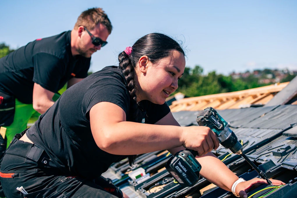 To elektrikere monterer solceller på en bolig. Foto.