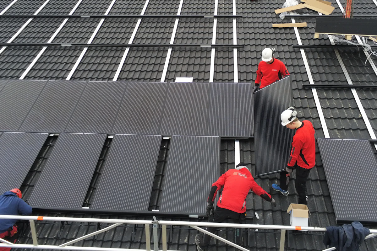Bilde av tre ansatte i Folldal Elektro som monterer solcellepanel på tak