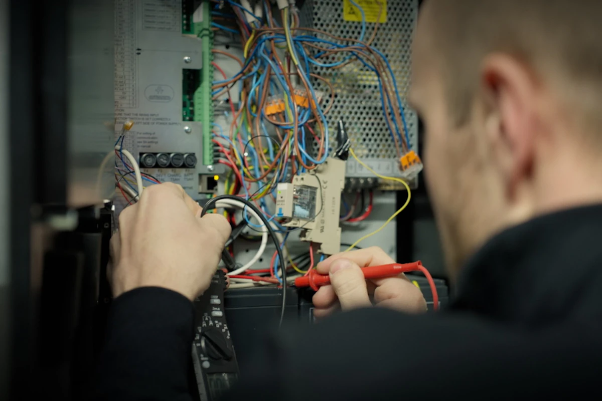 Elektriker som utfører arbeid og test i et sikringsskap. Bilde