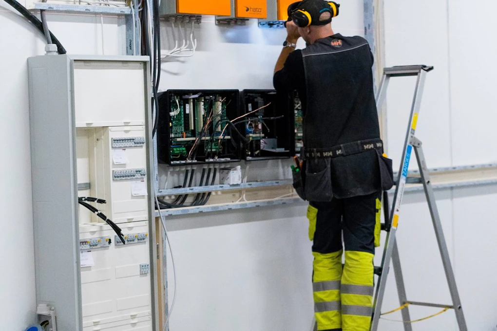 Elektriker jobber med fjørfecomputer i fjørfehus. Foto