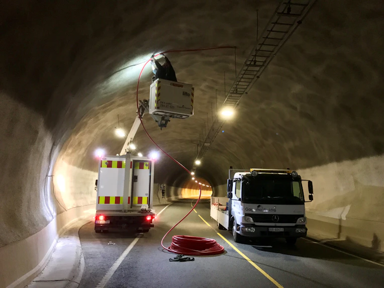 Elektroarbeid i tunnel med liftbil og lastebil